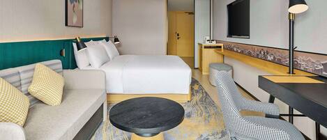 Una habitación de hotel con cama, sofá, escritorio, silla y televisor.