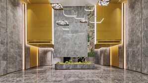 Eine moderne Lobby mit Marmorwänden, eingelassener Beleuchtung und einem zentralen Pflanzkübel mit Grünpflanzen.