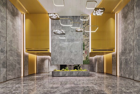Um lobby moderno com paredes de mármore, iluminação embutida e um jardim vertical central.