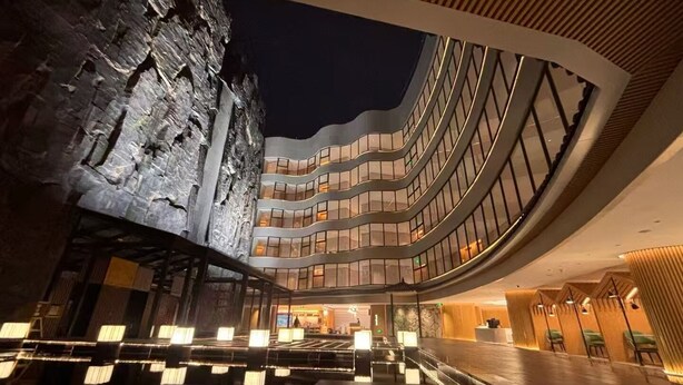 Ein modernes Hotel mit einer geschwungenen Fassade, mehreren Balkonen und einer großzügigen Lobby.