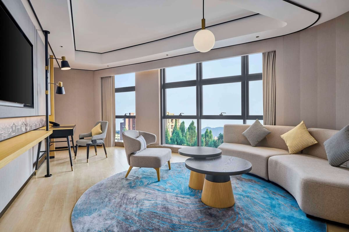 A modern living room with a large window, a sofa, a coffee table, and a TV.
