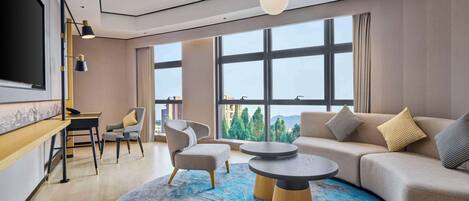 Una sala de estar moderna con un gran ventanal, un sofá, una mesa de centro y un televisor.