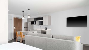 A modern kitchen with a built-in microwave, a coffee machine, and a flat-screen TV mounted on the wall. - Homewood Suites Holland (Holland)