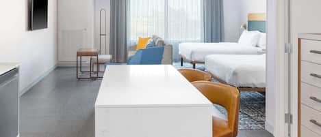 A hotel room with a white marble desk, two beds, a TV, and a window with curtains.