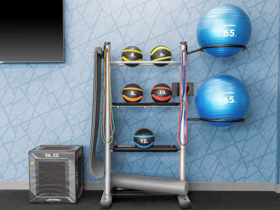Un ensemble d'équipement de remise en forme comprenant un support mural pour ranger différents ballons d'exercice et une plateforme de marche.