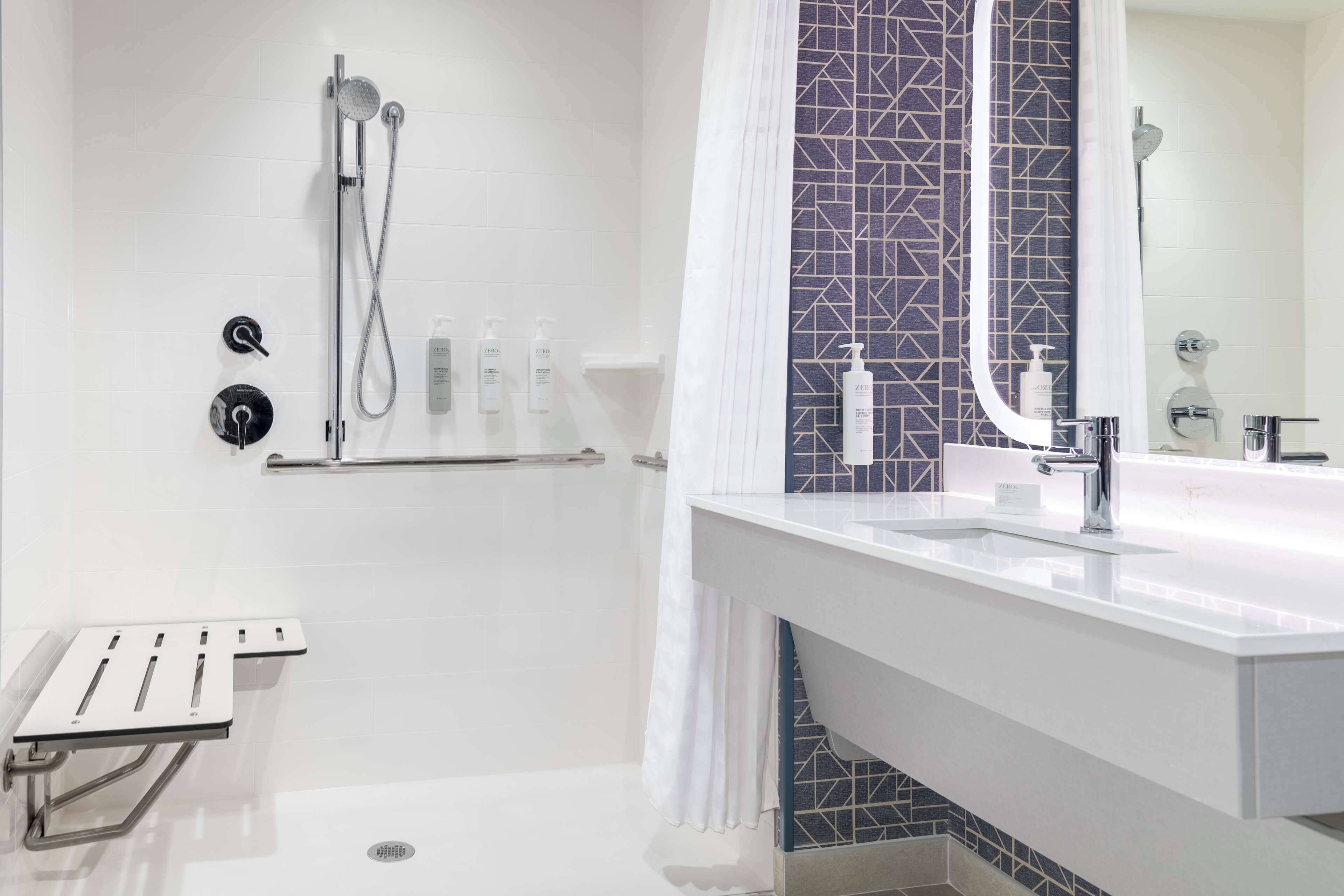 Un baño moderno con ducha, lavamanos y espejo.