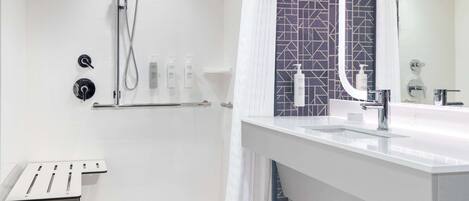 Un baño moderno con ducha, lavamanos y espejo.