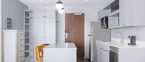 Una cocina moderna con armarios blancos, una isla central y un microondas integrado.