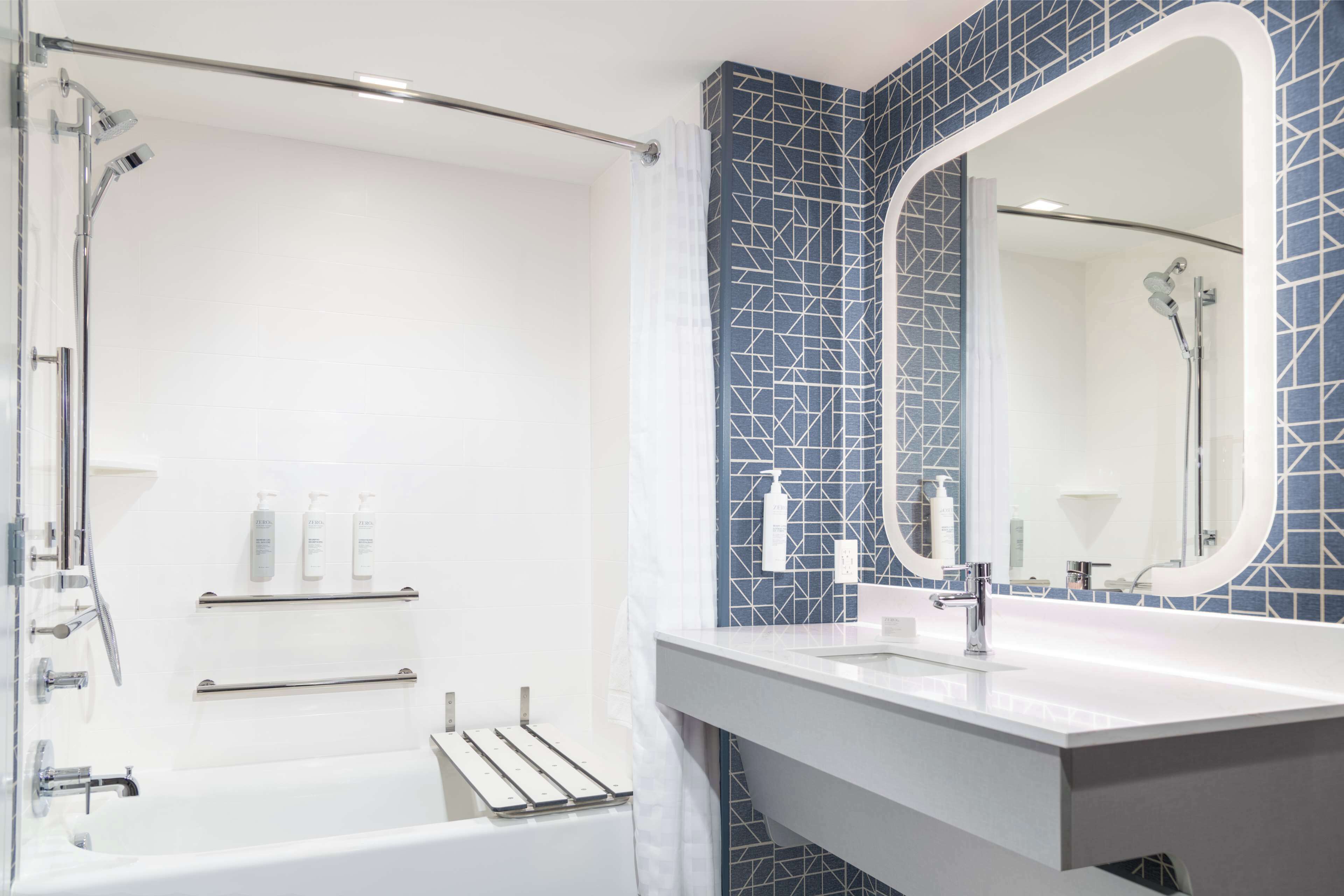 A modern bathroom with a bathtub, a large mirror, and a shower area.
