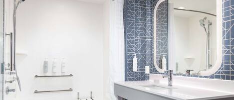 A modern bathroom with a bathtub, a large mirror, and a shower area.