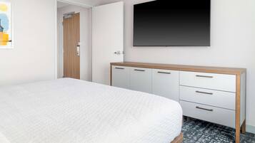 Ein Schlafzimmer mit einem Bett, einem Kleiderschrank, einem flachbildfernseher an der Wand und einer Tür zu einem anderen Raum.