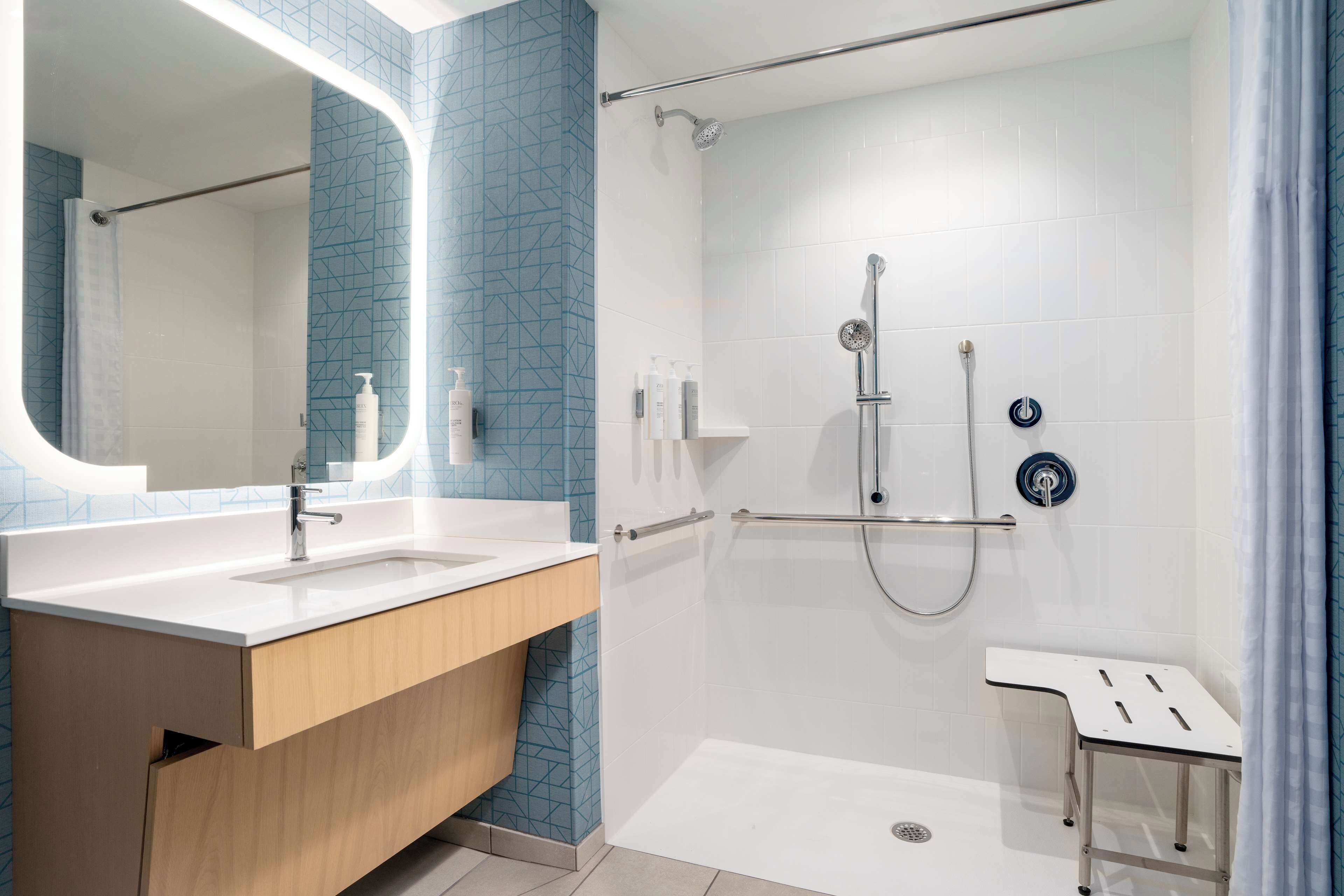 A modern bathroom with a shower, a sink, and a mirror.