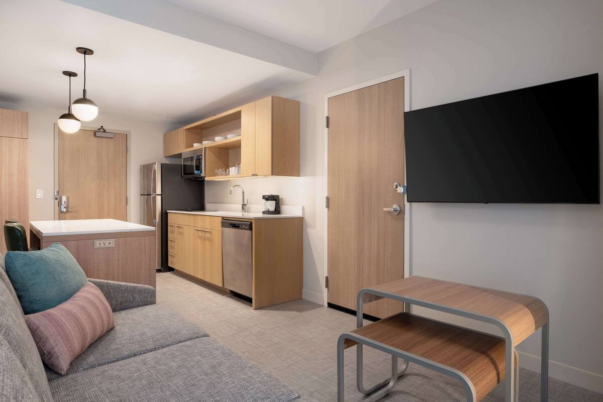 A compact kitchen with wooden cabinets, a built-in microwave, and a stainless steel refrigerator.