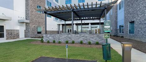 A modern building with a covered outdoor area, a pet wash sign, and a well-maintained lawn.