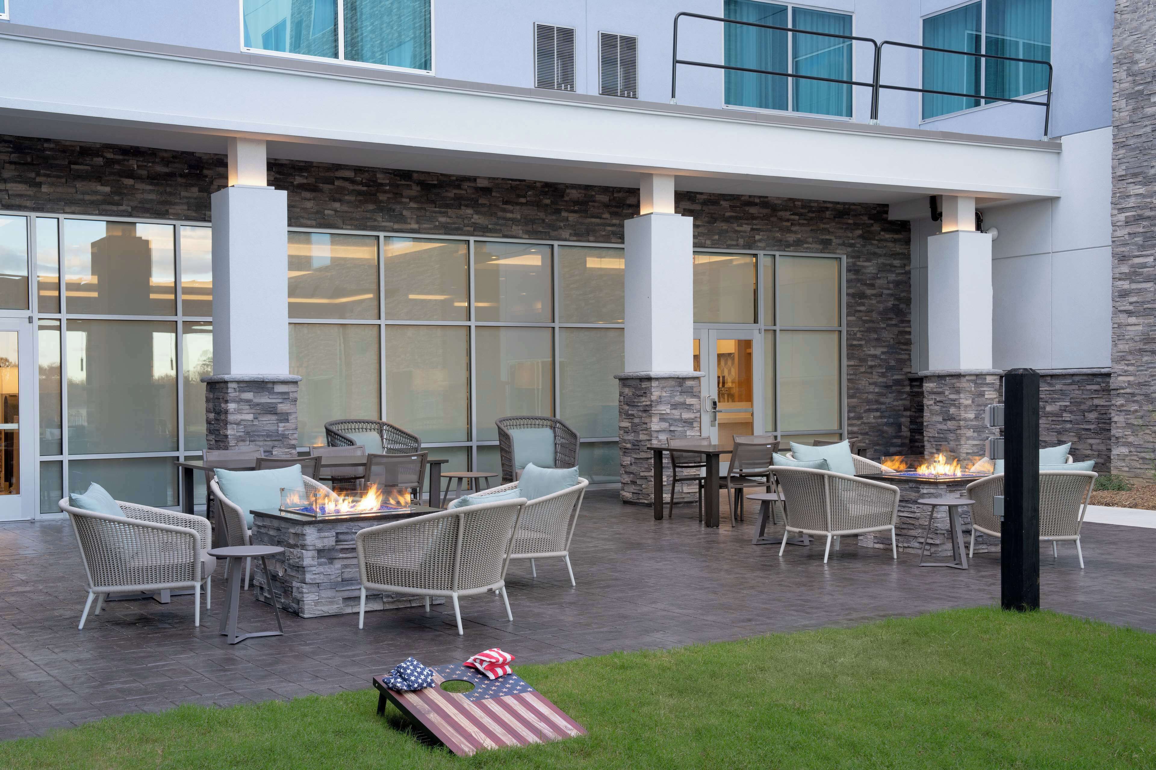 An outdoor patio with wicker furniture, a fire pit, and a stone wall.