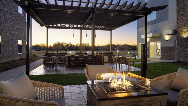 Eine Terrassensitzgruppe im Freien mit Feuerschale, Sitzgelegenheiten und einer Pergola.