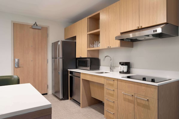 Una cocina moderna con armarios de madera, un refrigerador de acero inoxidable, un microondas, una cafetera y un lavamanos.