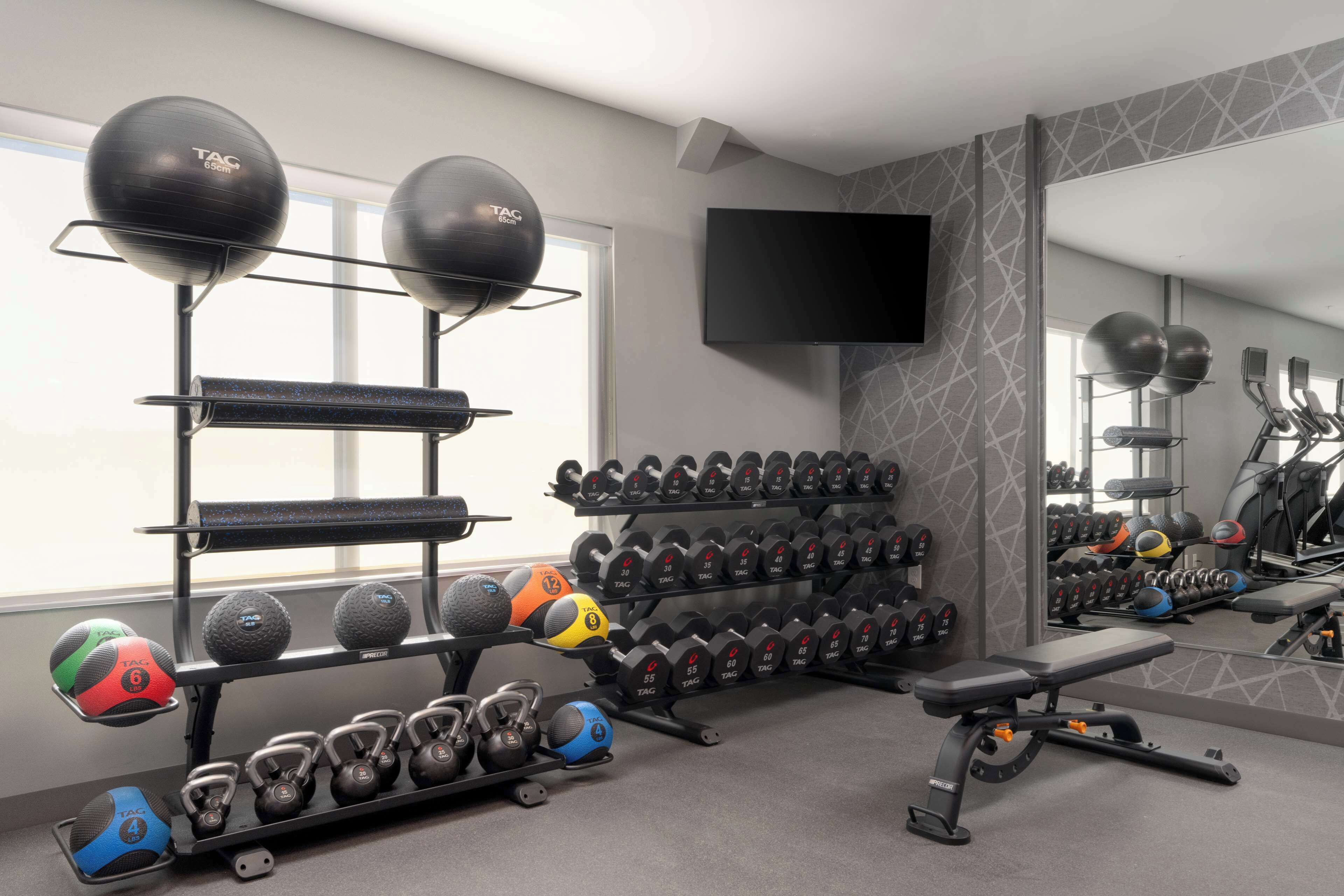 A gym with exercise equipment, a TV, and a mirror.