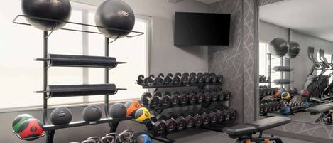A gym with exercise equipment, a TV, and a mirror.