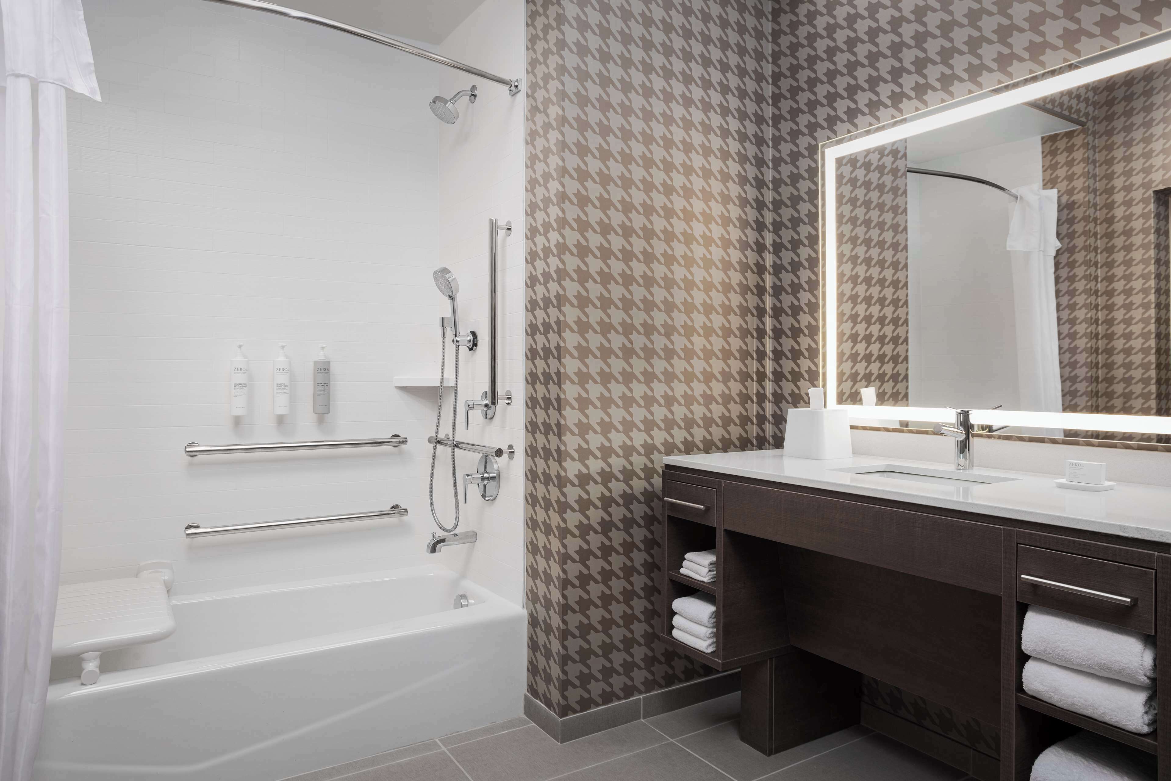 Un baño moderno con bañera, ducha, tocador y un espejo grande.