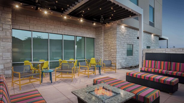 An outdoor patio with seating, a fire pit, and a stone wall. - Home2 Suites By Hilton Laredo North (Laredo)