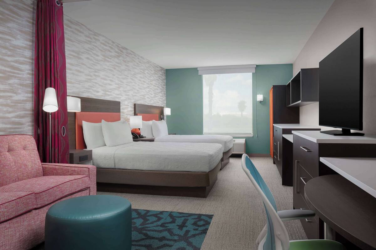 A hotel room with a bed, a desk, a chair, a TV, and a window.
