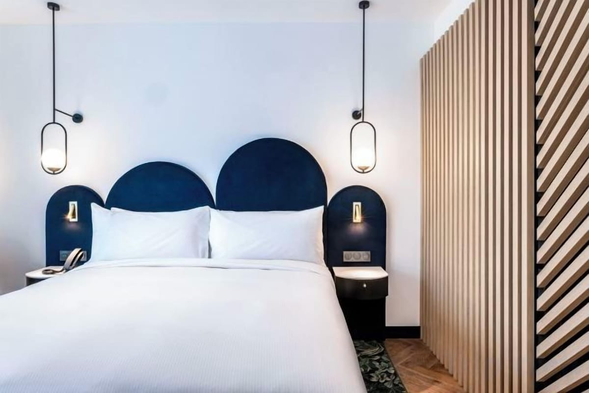A hotel room with a large bed, two bedside tables, and a modern headboard.