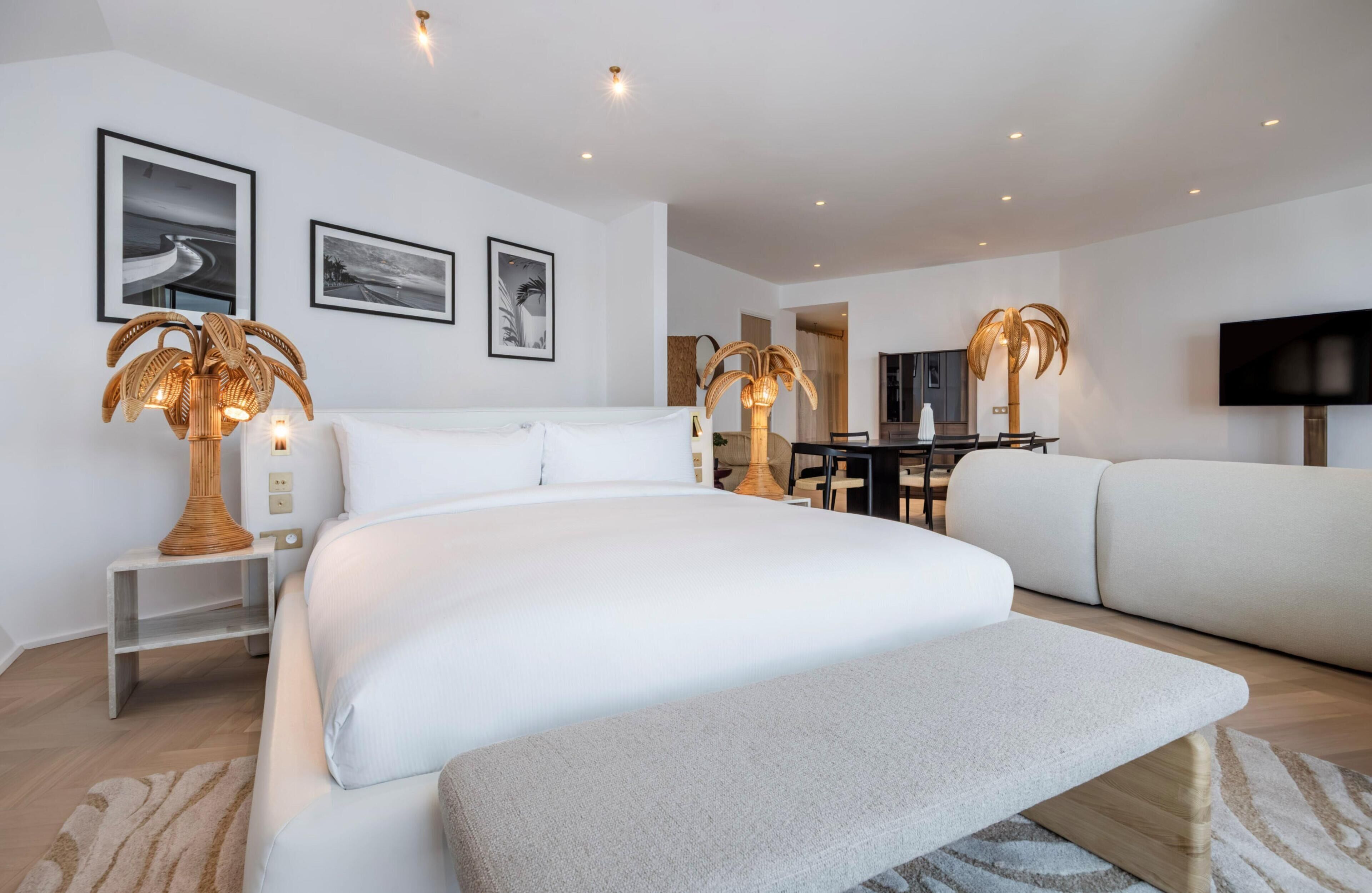 Et moderne hotelværelse med en stor seng, en sofa, et spisebord og et fjernsyn.