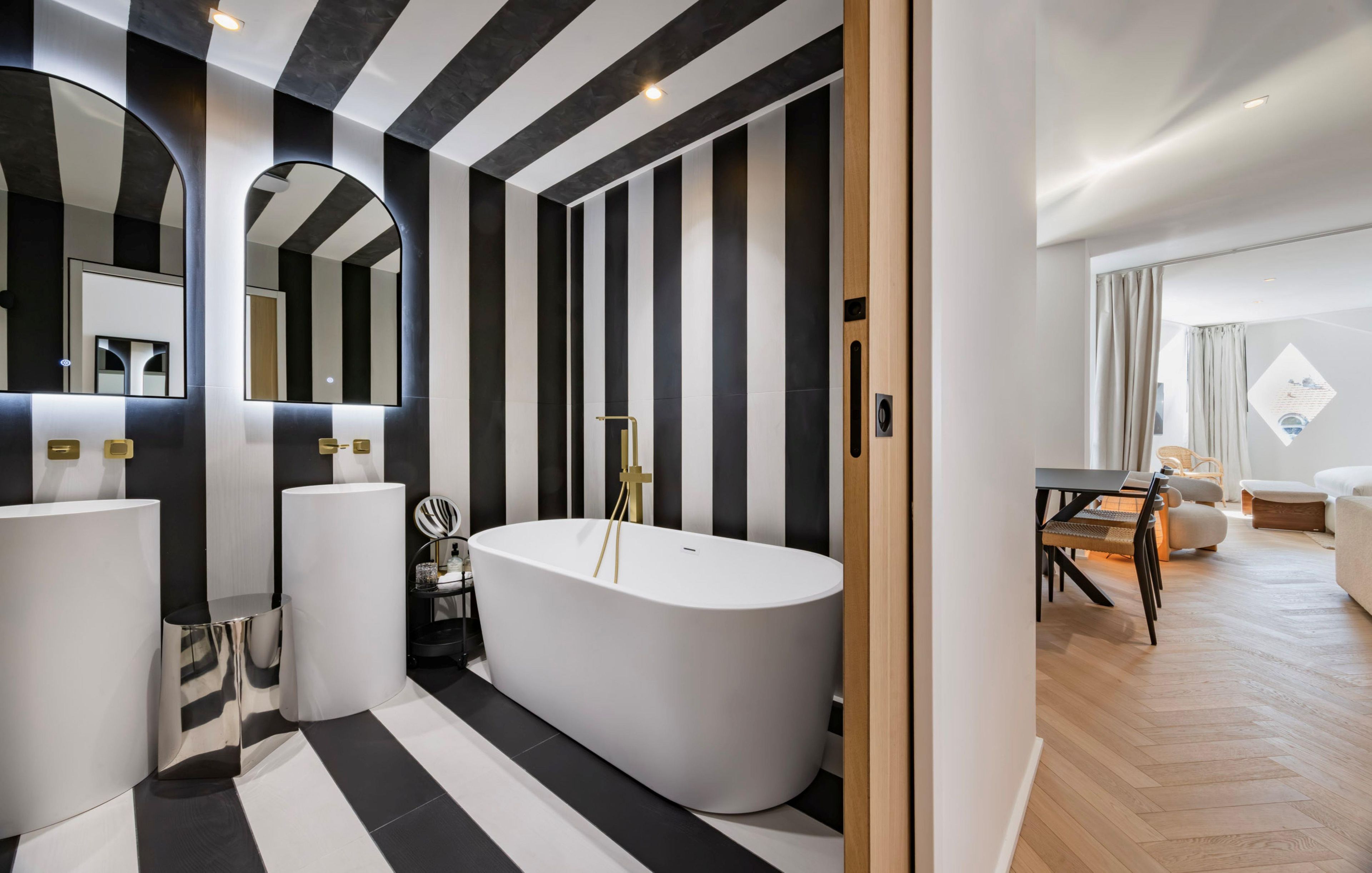 A modern bathroom with a freestanding bathtub, a large mirror, and a black and white striped floor.