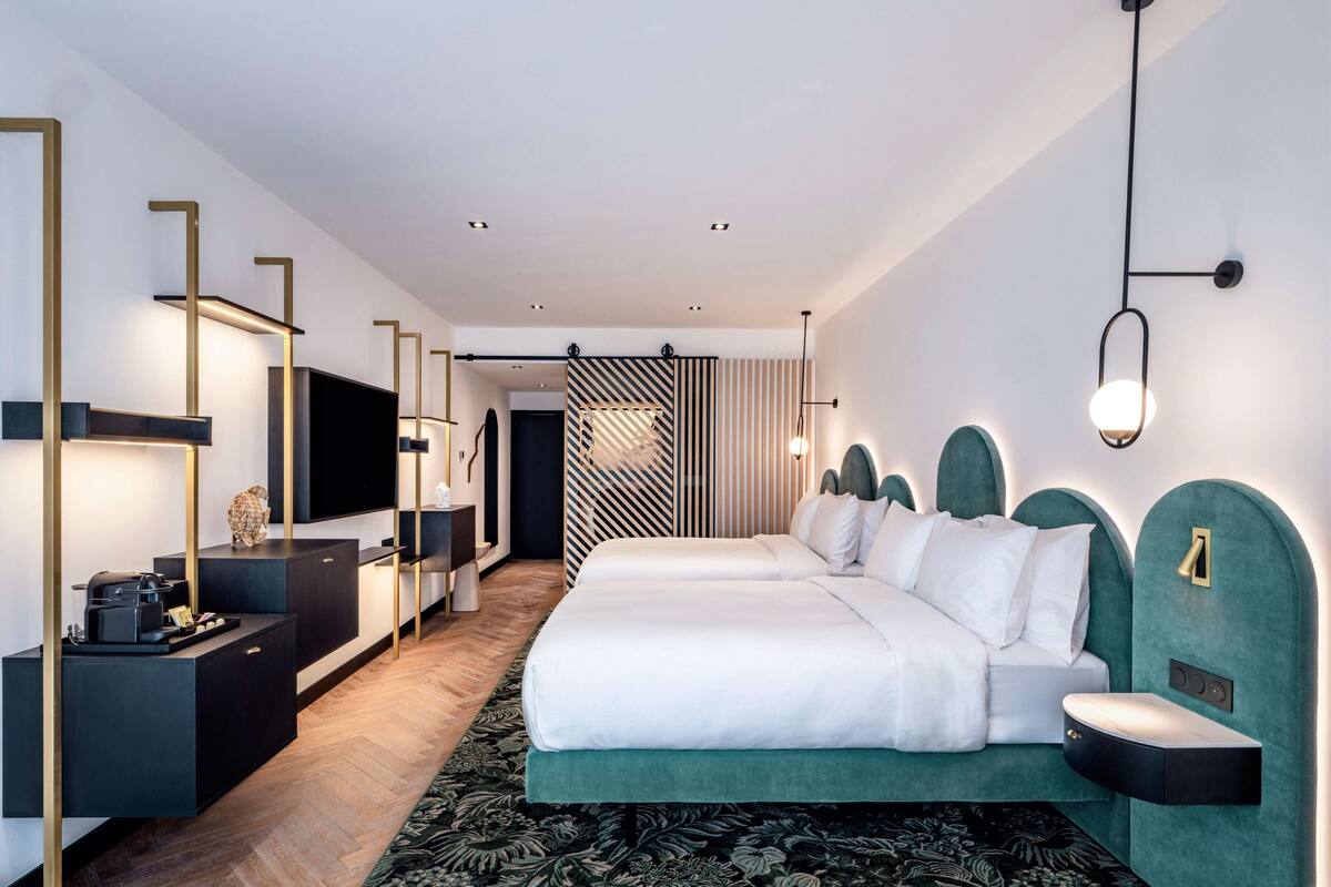 A modern hotel room with a large bed, a desk with a flat-screen TV, and a separate seating area.
