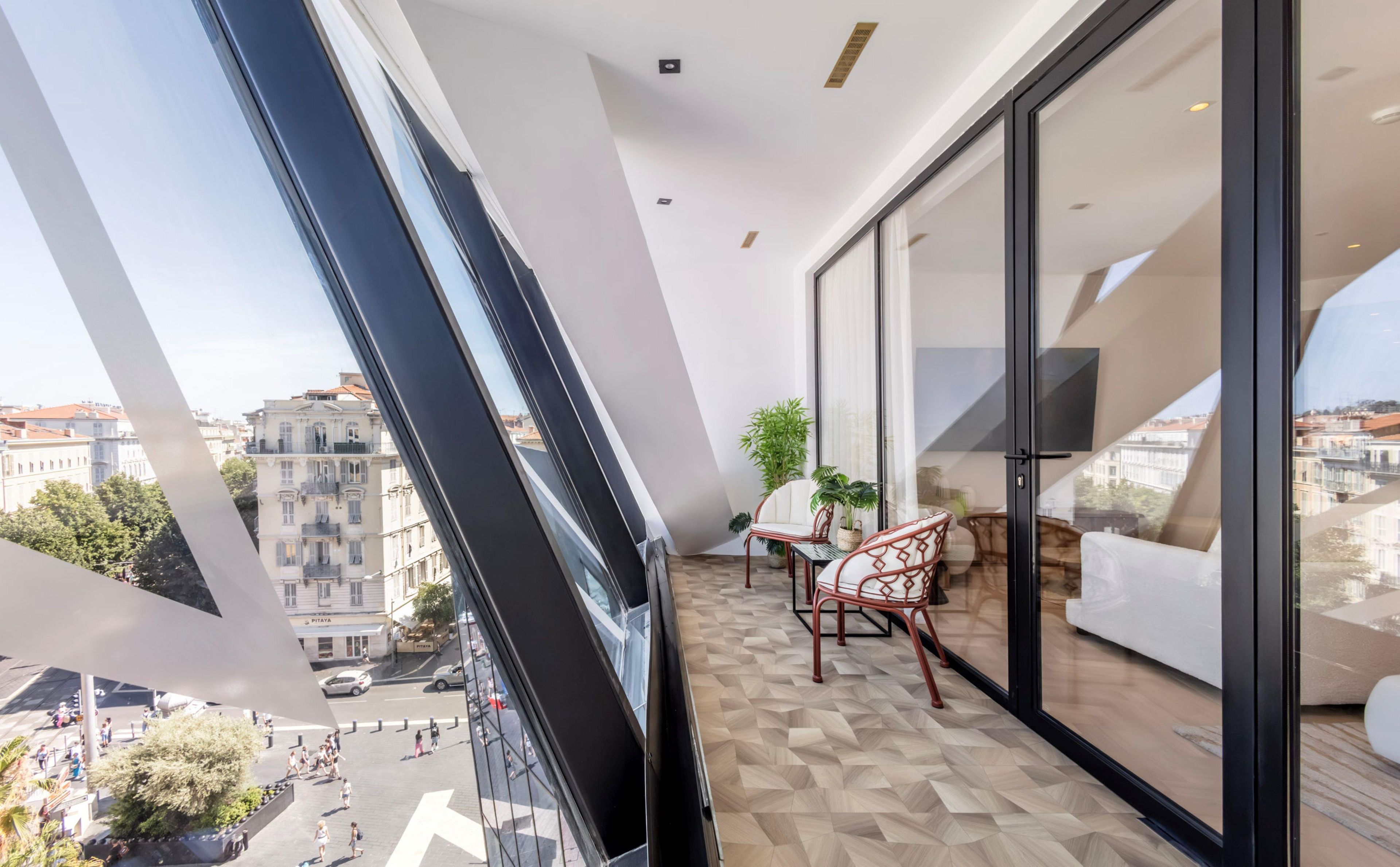 Un balcon avec vue sur la ville, un canapé, un fauteuil et une plante en pot.