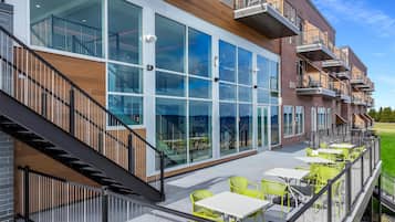 Un edificio moderno con amplios ventanales, asientos exteriores y una escalera.