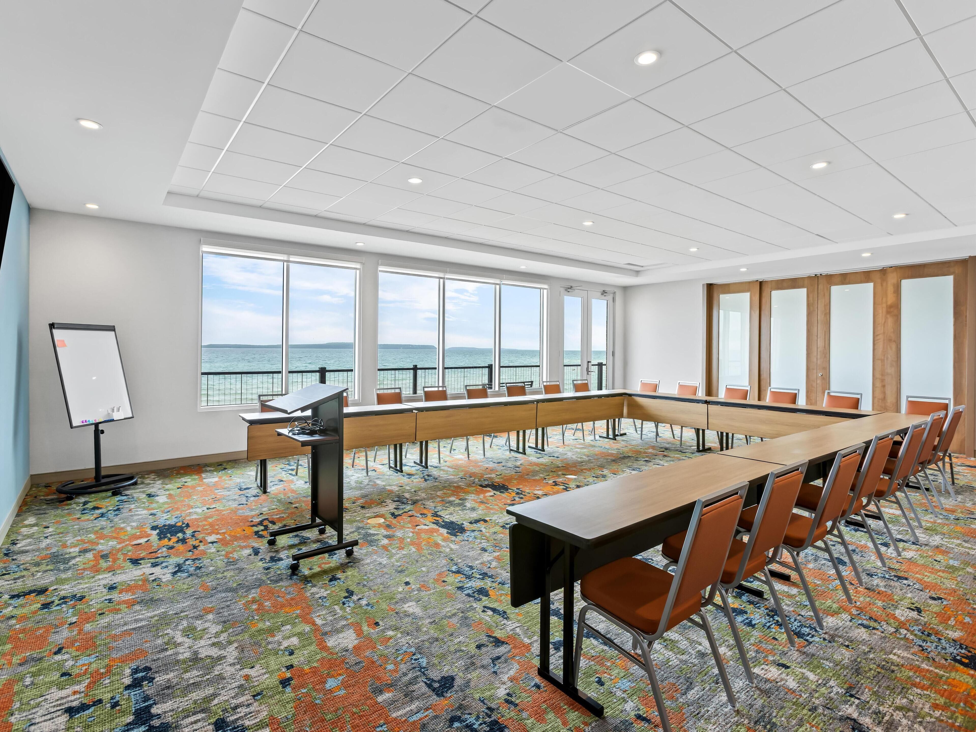 Une salle de conférence équipée d’une grande table, de chaises, d’un tableau blanc et de grandes fenêtres donnant sur la mer.