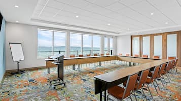 Une salle de conférence équipée d’une grande table, de chaises, d’un tableau blanc et de grandes fenêtres donnant sur la mer.