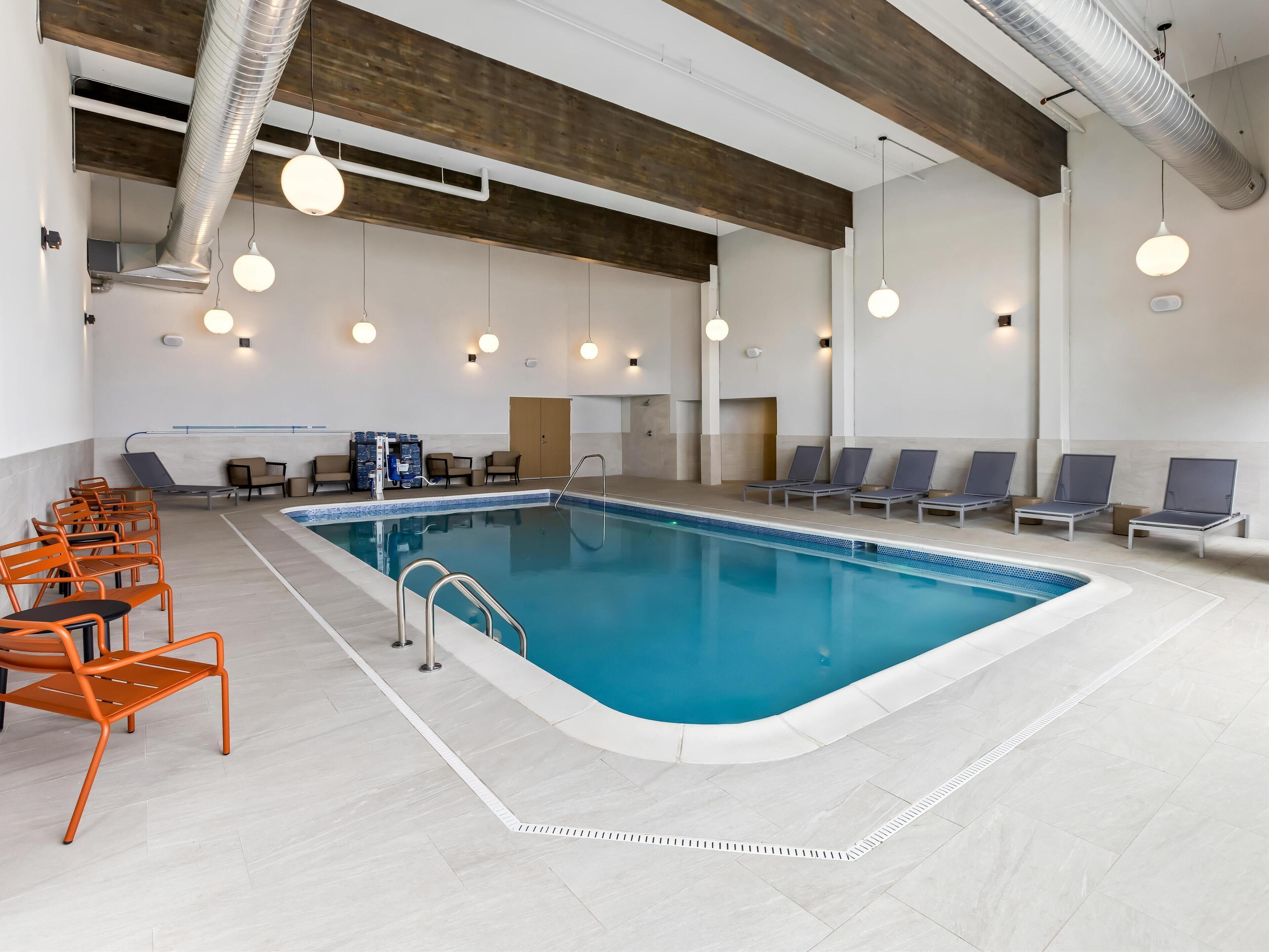 An indoor swimming pool with lounge chairs and a changing room.
