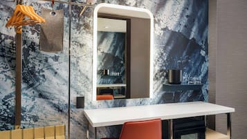 A modern bathroom with a marble wall, a white sink, a mirror, and a towel rack.