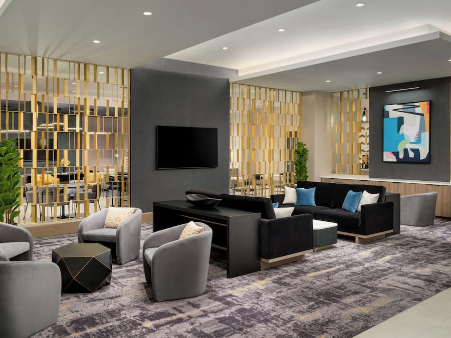 Una sala de estar moderna con un sofá, sillones, una mesa de centro y un televisor.