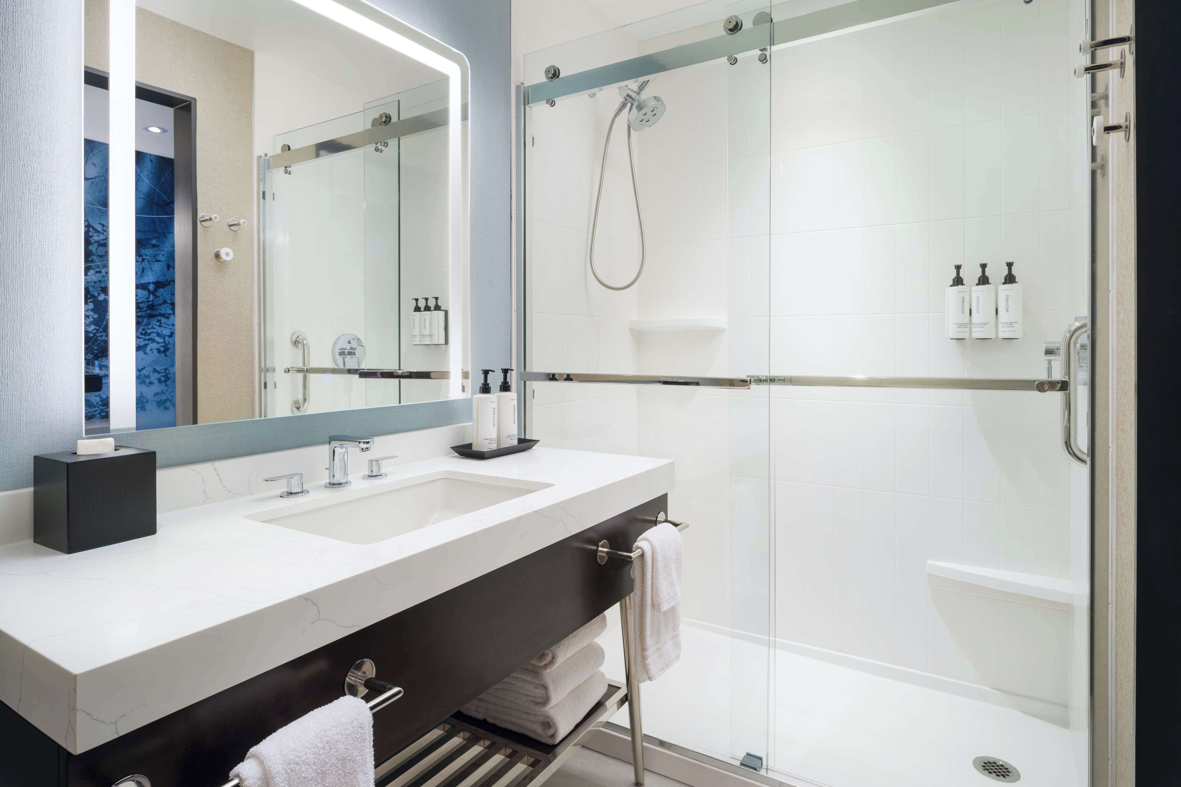 Un baño moderno con tocador de doble lavabo, ducha con cerramiento de vidrio y un espejo grande.