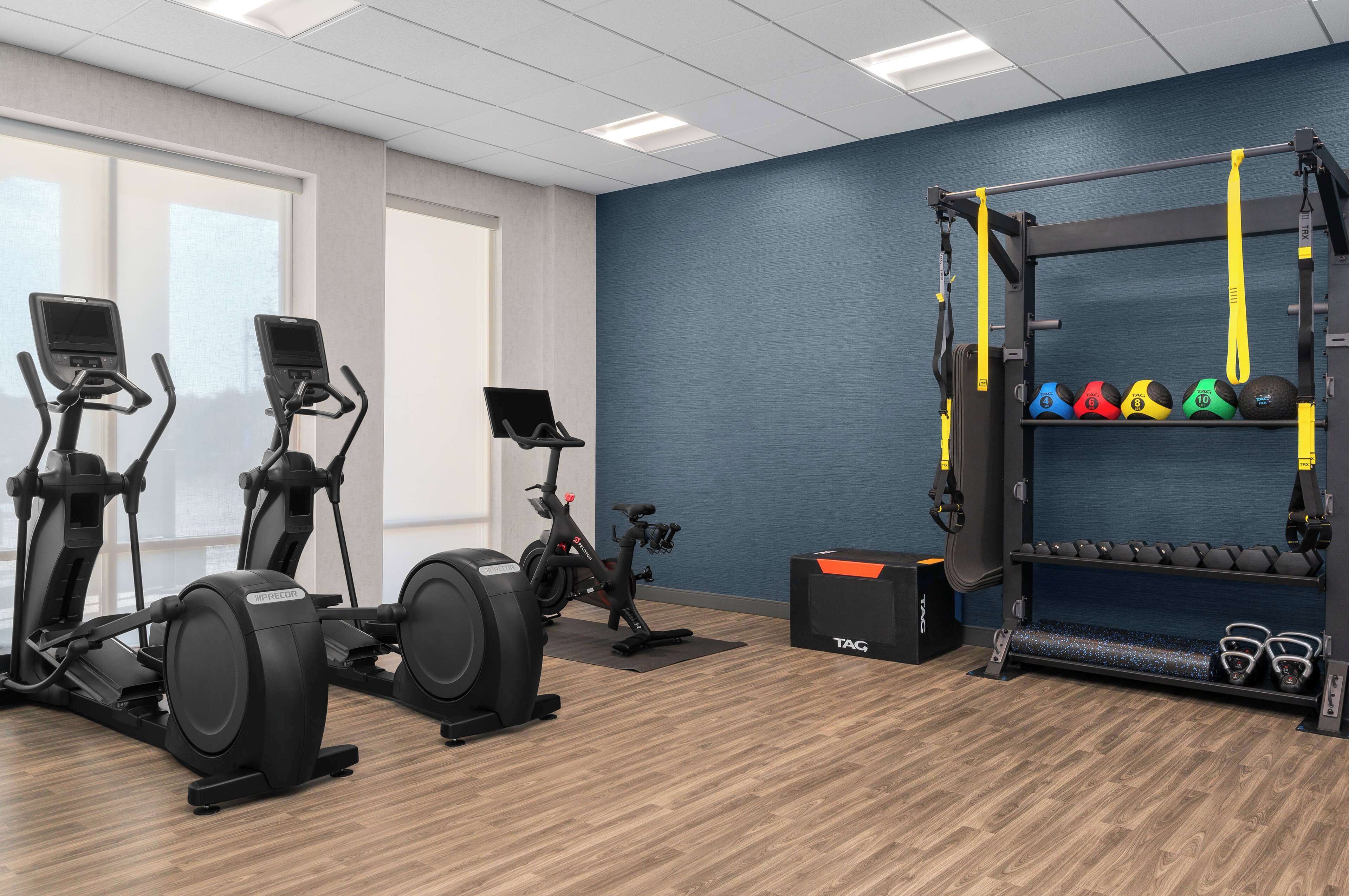 Une salle de sport équipée de tapis de course, d’un vélo elliptique, d’un vélo d’appartement, d’un support à squats et d’haltères.