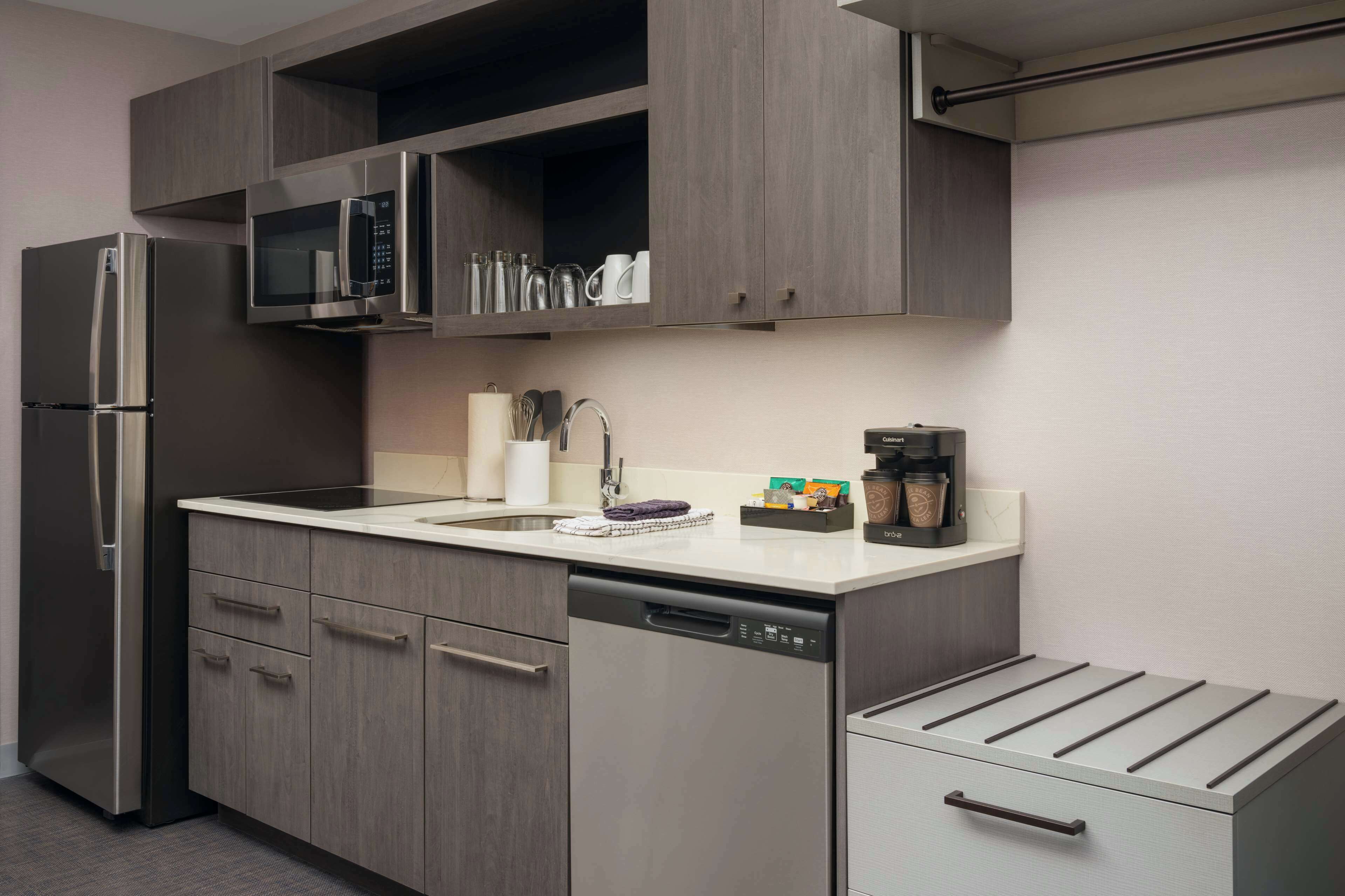A modern kitchen with a stainless steel refrigerator, a built-in microwave, a dishwasher, and a coffee maker.