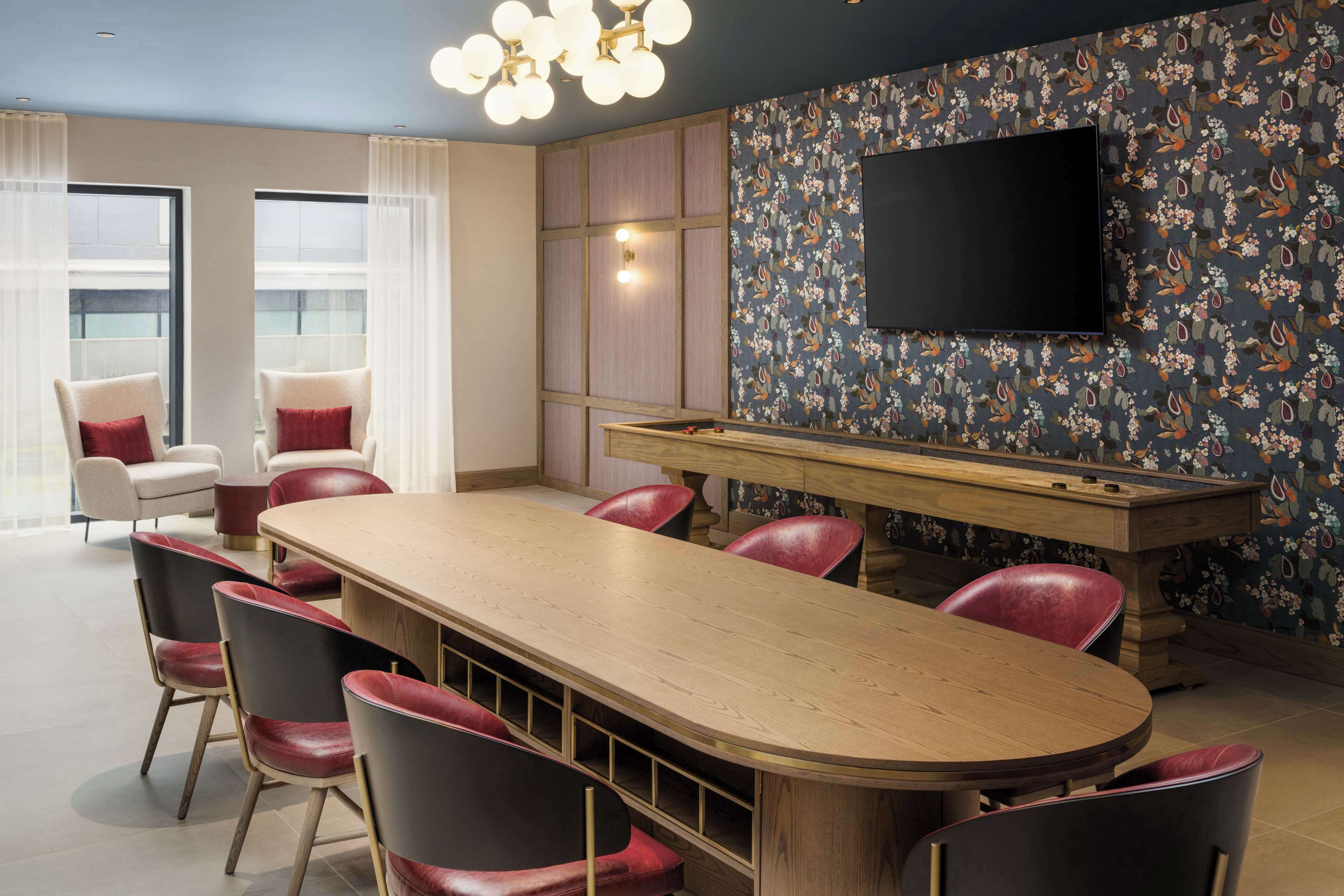 A modern lounge area with a pool table, comfortable seating, and a large TV screen.
