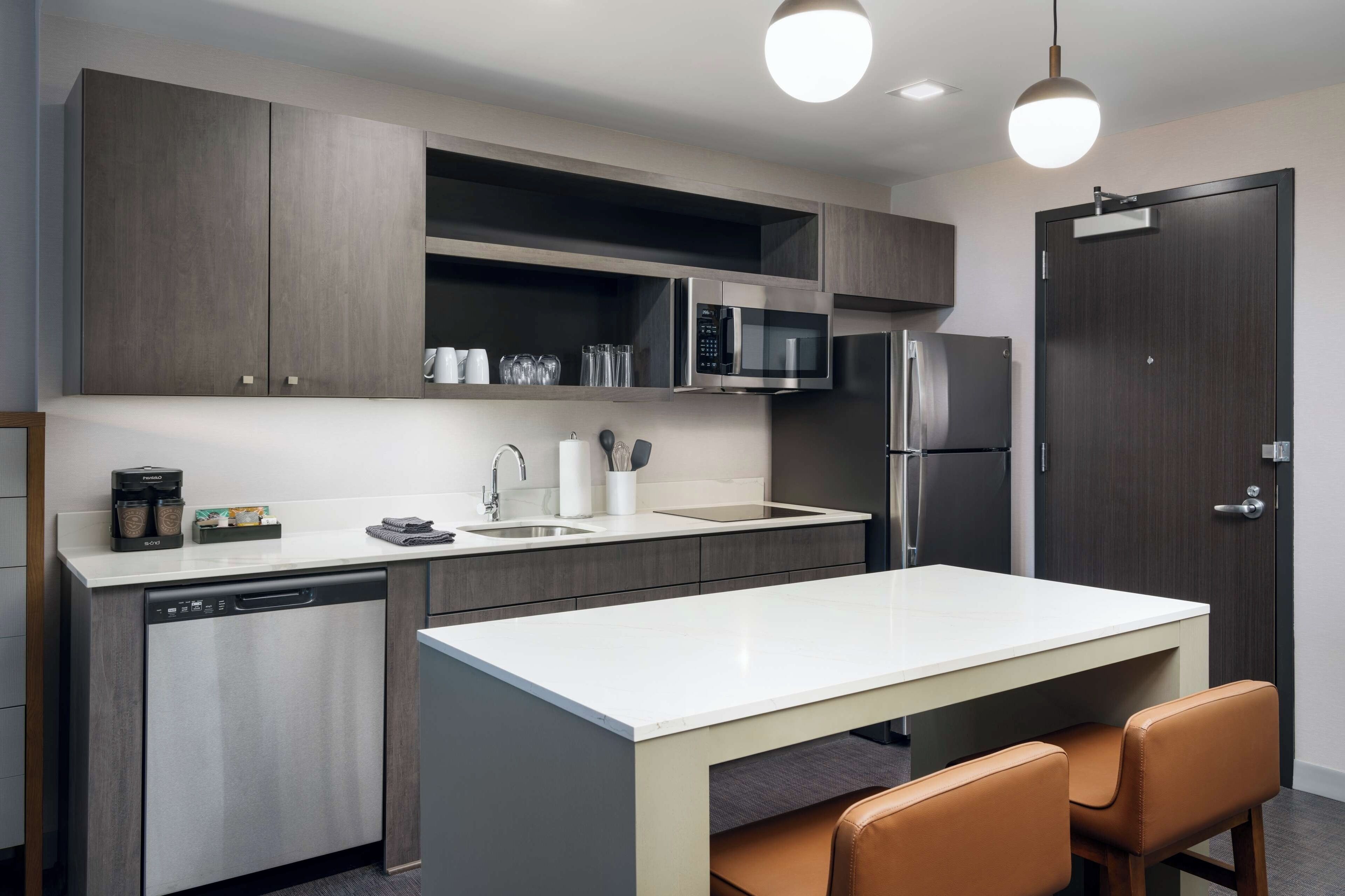 A modern kitchen with a dishwasher, microwave, refrigerator, and a dining area with a table and chairs.