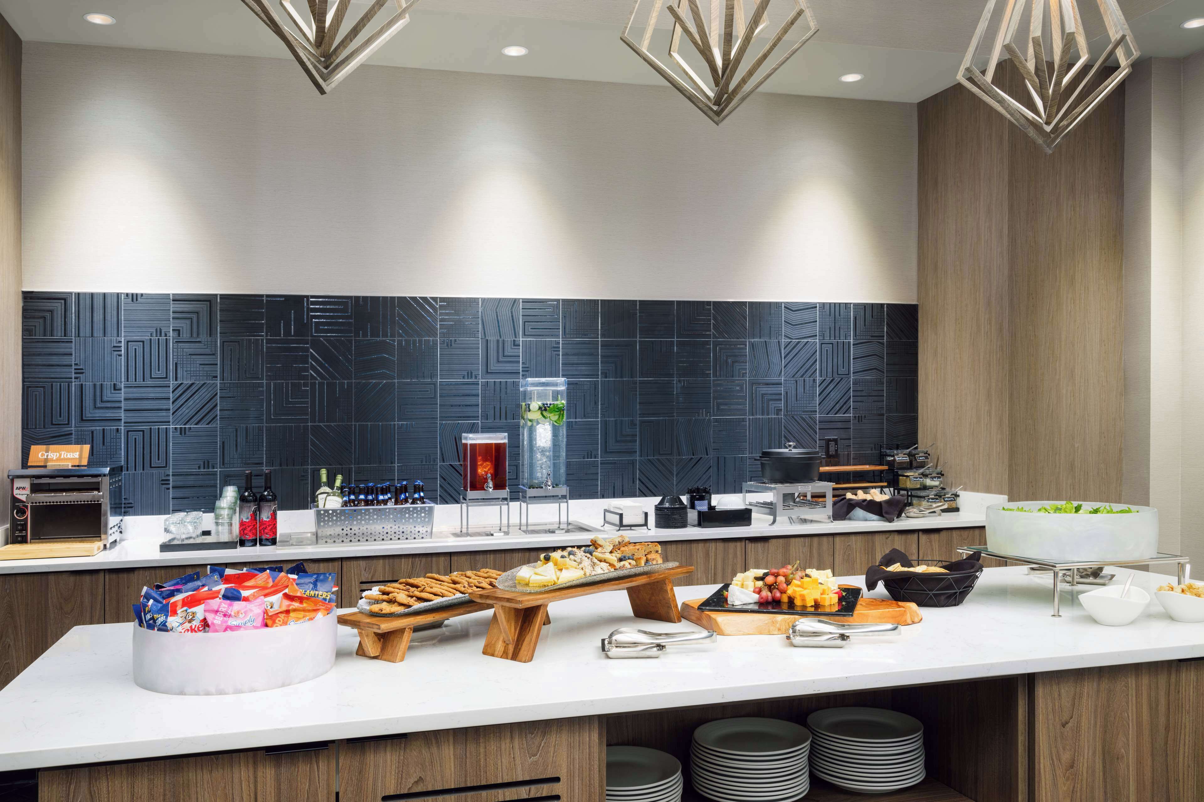 Une cuisine moderne avec un long comptoir, divers aliments et un mur décoratif.