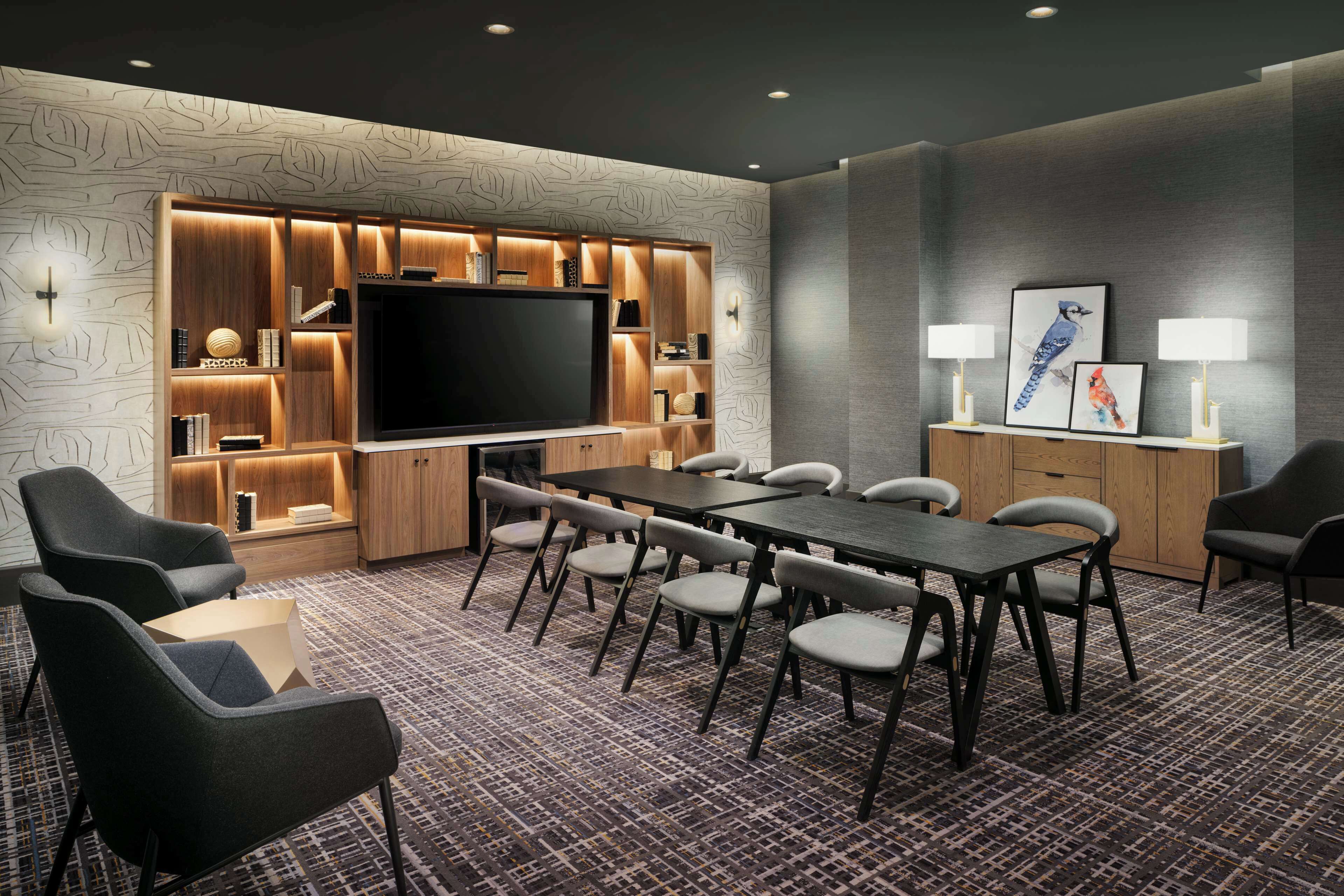 A conference room with a large flat-screen TV, a long table, and multiple chairs.