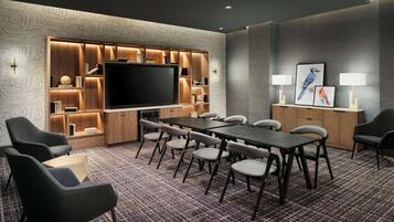 A conference room with a large flat-screen TV, a long table, and multiple chairs.