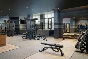 A gym with various exercise equipment, including benches, weight machines, and a rowing machine. - Homewood Suites by Hilton Raleigh Downtown (Raleigh)