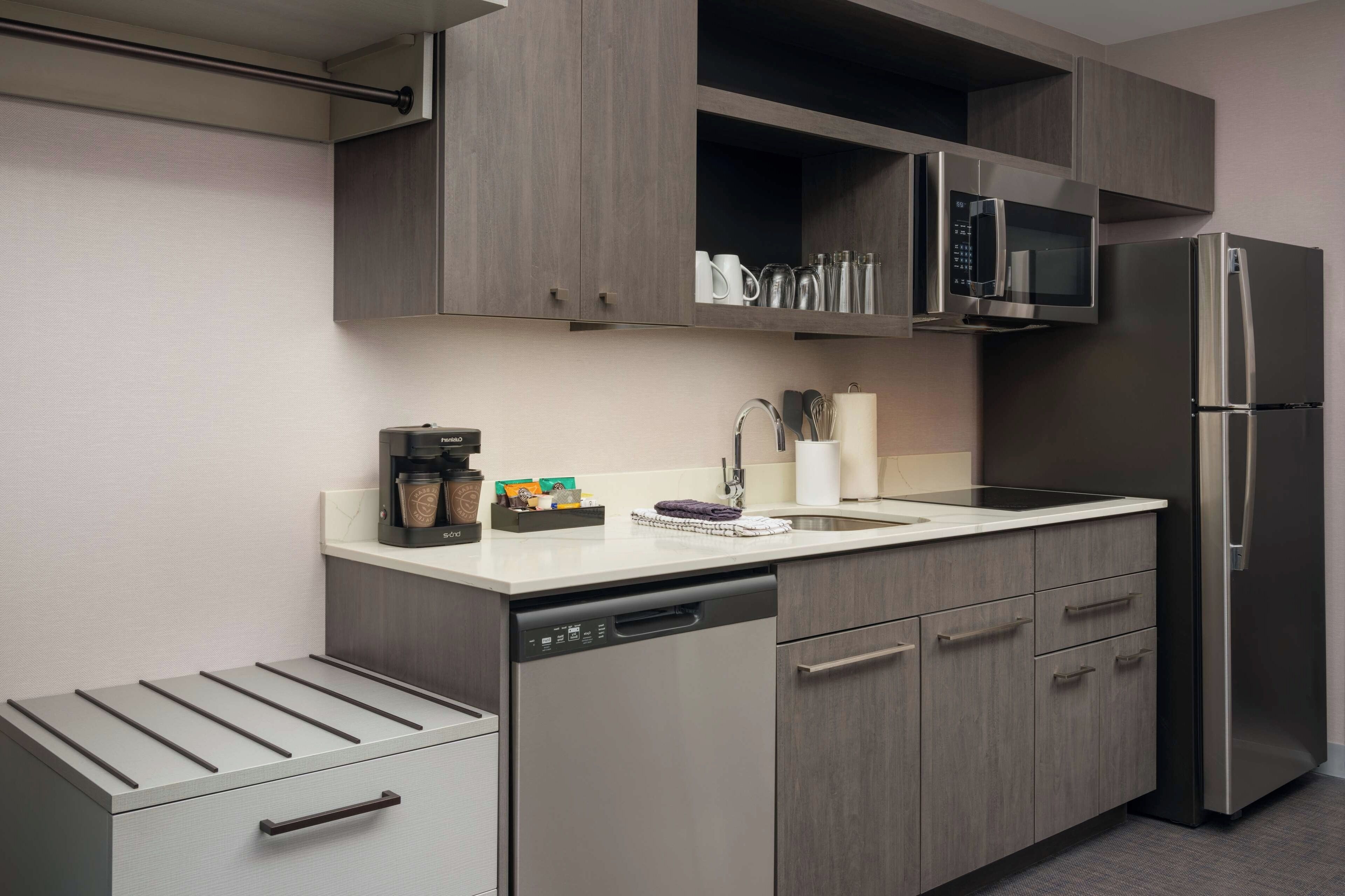 A modern kitchen with a dishwasher, stainless steel appliances, and wooden cabinets.