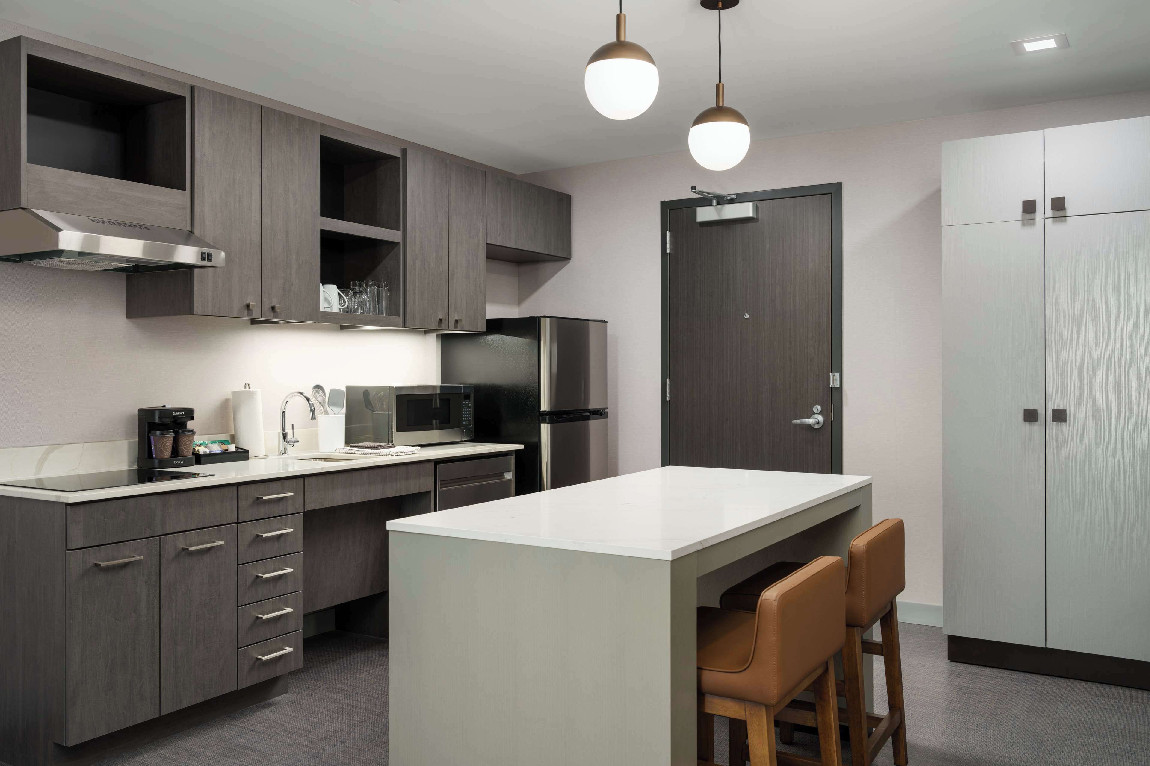 Una cocina moderna con armarios grises, una isla central y un microondas integrado.
