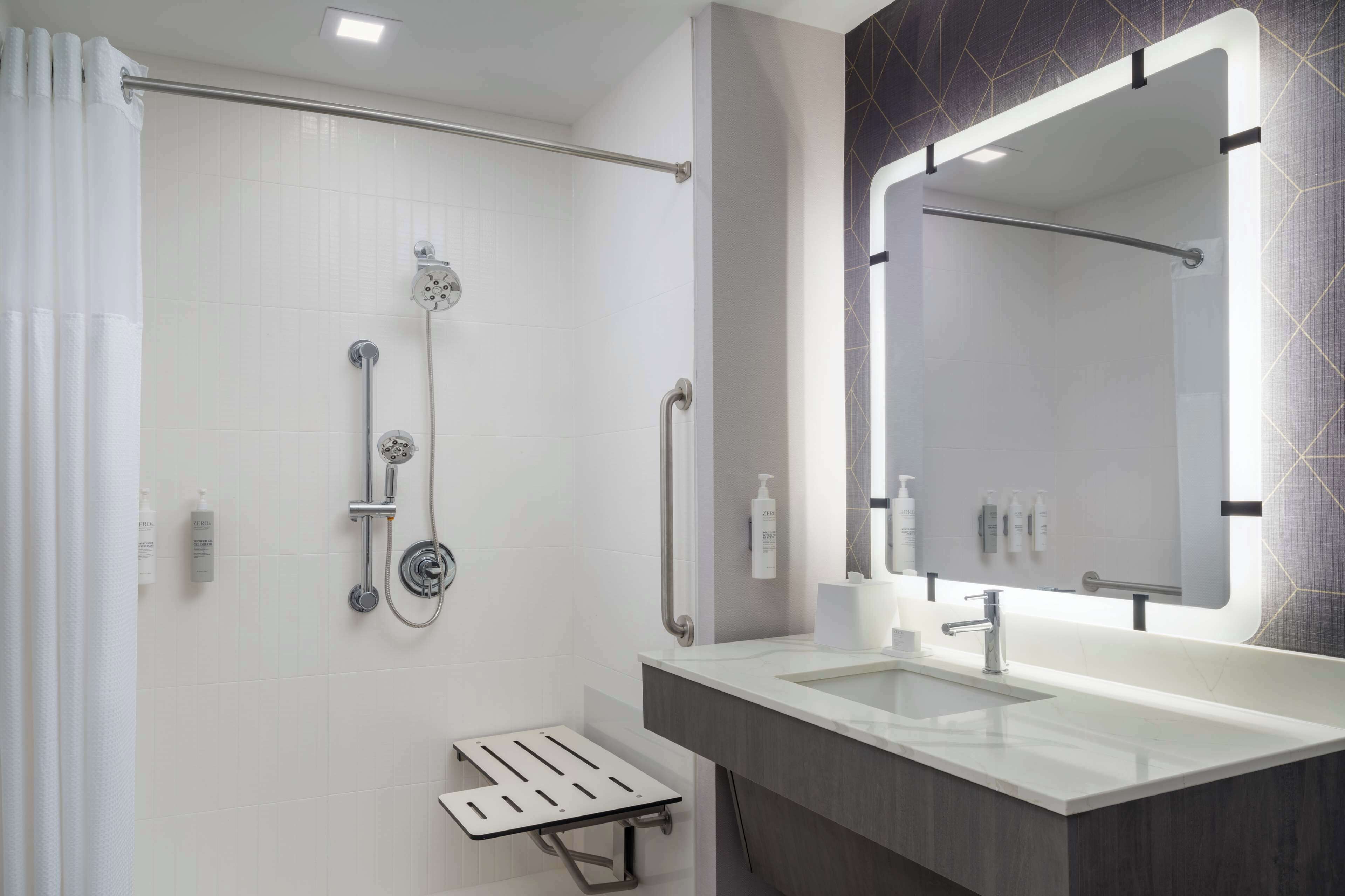 A modern bathroom with a walk-in shower, a large mirror, and a vanity with a sink.