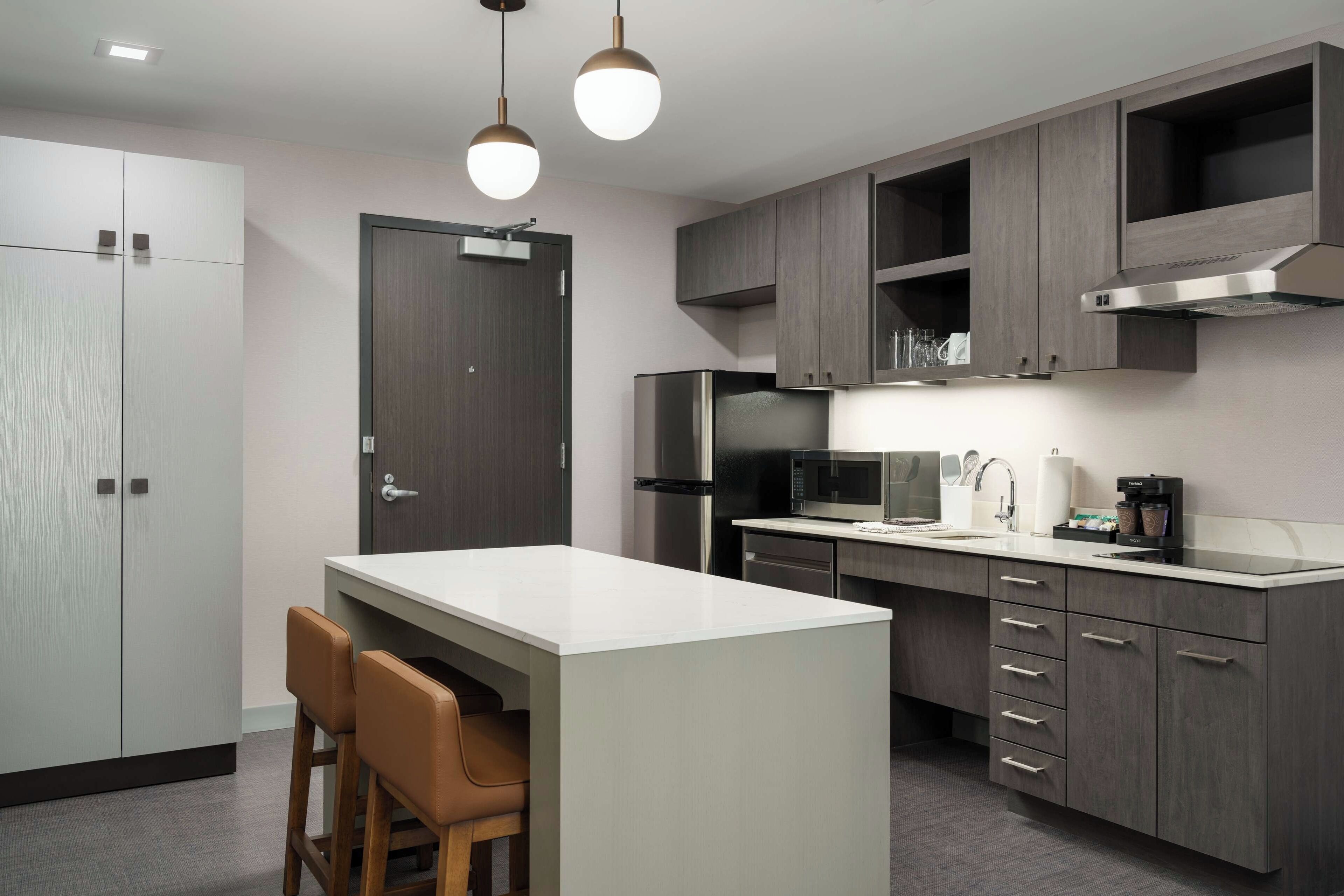 A modern kitchen with a central island, built-in appliances, and a bar seating area.